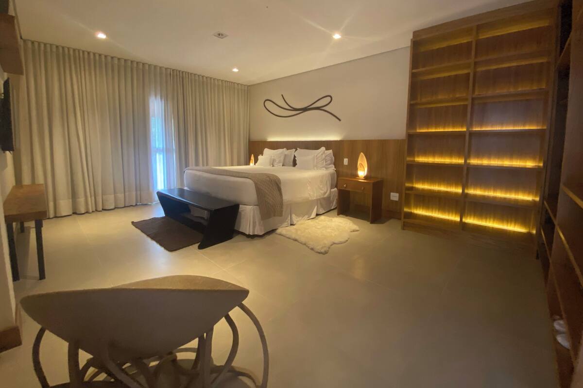 A modern bedroom with a large bed, bedside tables, a desk, and a decorative wall panel.
