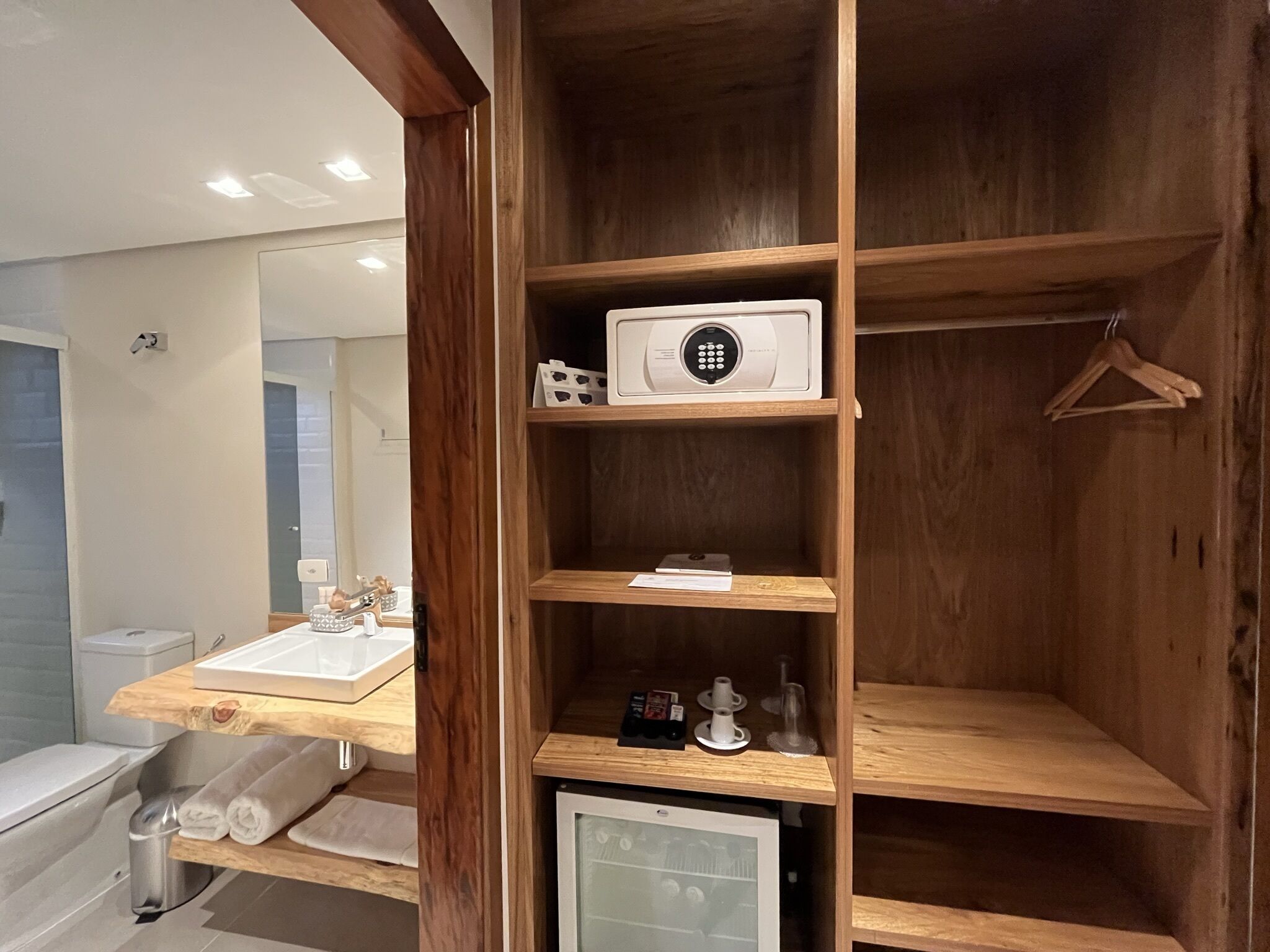 A bathroom with a wooden vanity, a microwave, and a small refrigerator.