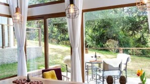 A room with large windows, a wooden table, and a view of the outdoors.