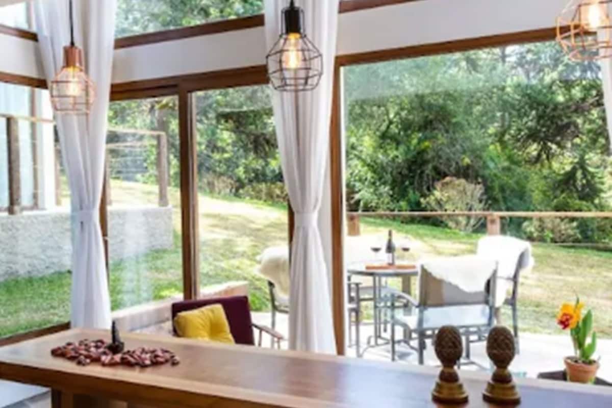 A room with large windows, a wooden table, and a view of the outdoors.