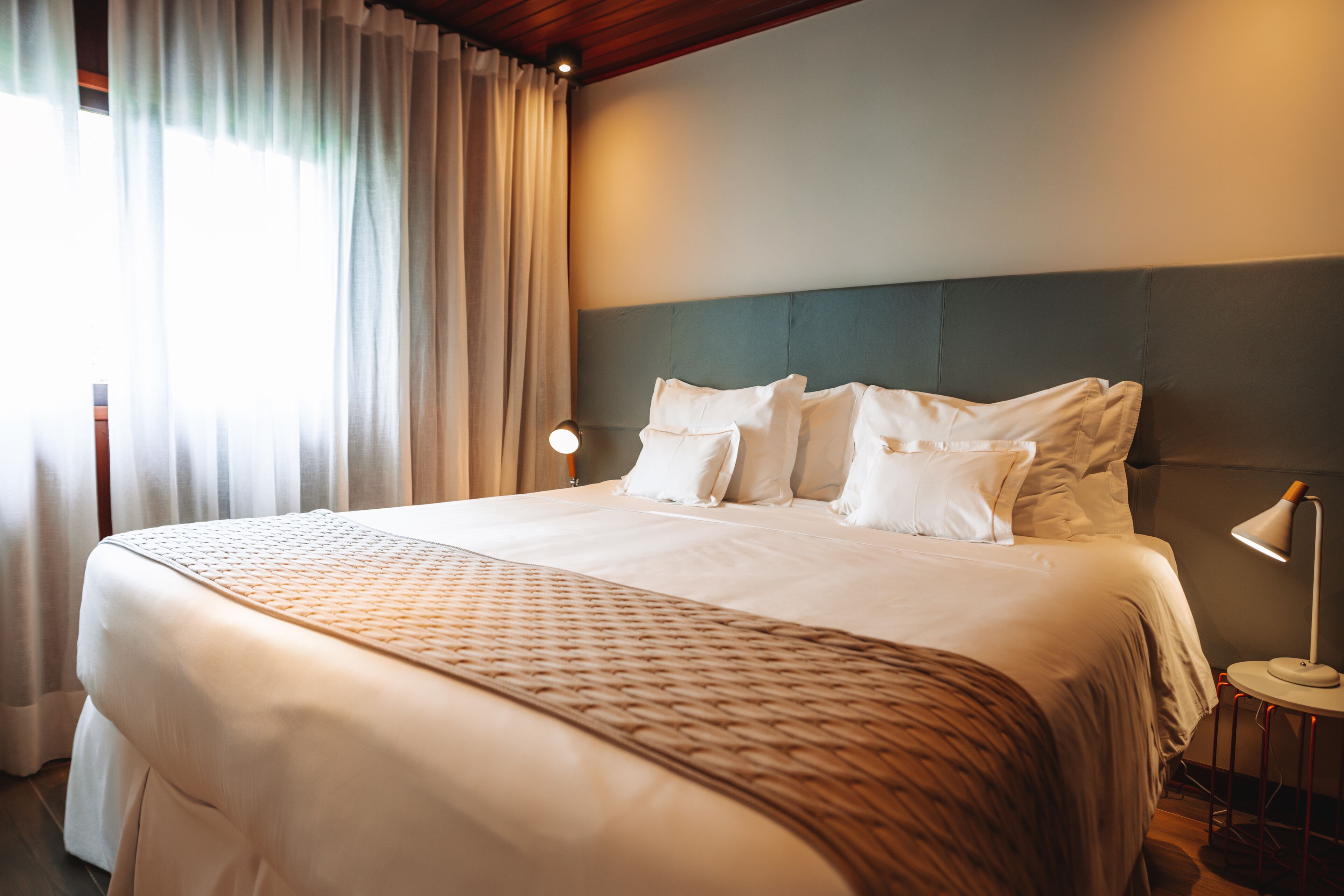 A neatly made bed with a patterned bedspread, a headboard, and two bedside lamps.