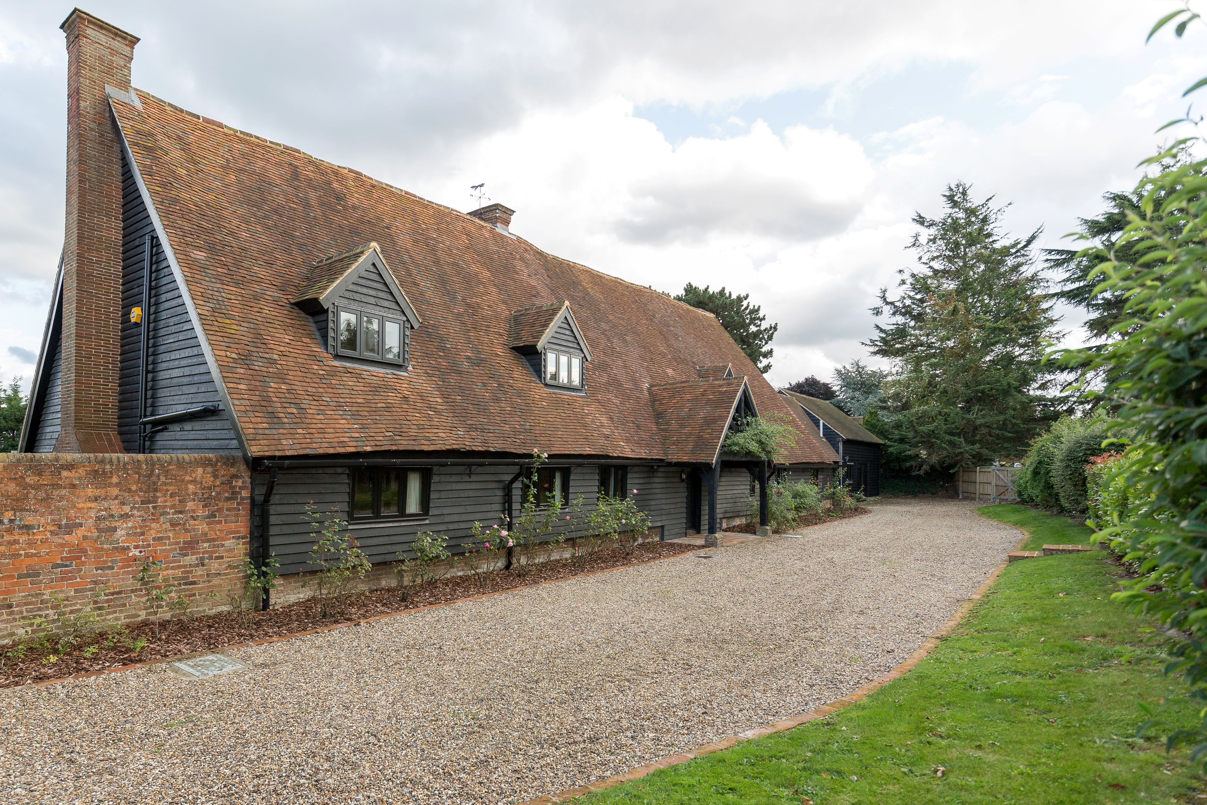 A traditional brick house with a gravel driveway and a grassy area.