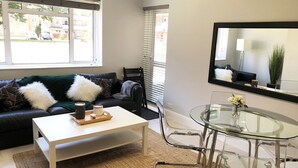 Ein modernes Wohnzimmer mit einem schwarzen Ledersofa, einem weißen Couchtisch und einem Glastisch für Essenszeiten.