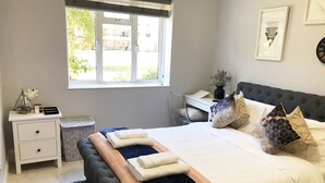Ein Schlafzimmer mit Bett, Nachttischen, Schreibtisch und Fenster.