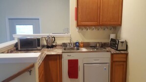 Eine kompakte Küche mit Mikrowelle, Toaster, Spüle und Geschirrspüler.