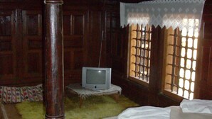 A room with a bed, a television on a small table, and a window with a lace curtain. - Zarkovata Kashta (Kotel)