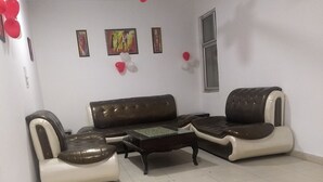 Un salon avec un canapé en cuir marron, une table basse en verre et un ventilateur de plafond.