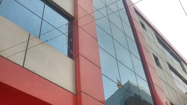 Un bâtiment moderne à la façade rouge et blanche, doté de grandes fenêtres et d’un escalier apparent.