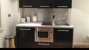 Una cocina moderna con gabinetes negros, electrodomésticos de acero inoxidable y encimera blanca.