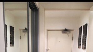 Un pasillo con piso de madera, paredes blancas y una puerta cerrada.