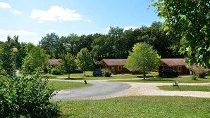 A campground with multiple cabins, a gravel driveway, and surrounding greenery. - Village du Soleil (Mauroux)