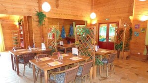 A wooden interior with stone flooring, tables with chairs, and a visible door labeled "EXIT". - Village du Soleil (Mauroux)