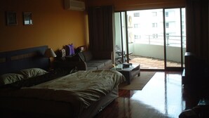 Ett hotellrum med en stor säng, en soffa, en TV och en balkong med utsikt över en byggnad.