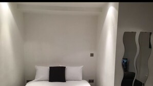 A modern hotel room with a large bed, white walls, and a unique wall art piece. - The Greengate Apartment (Salford)