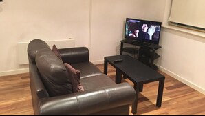 A living room with a leather sofa, a coffee table, and a flat-screen TV. - The Greengate Apartment (Salford)