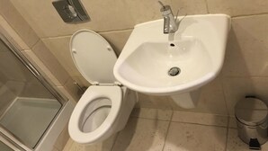 A bathroom with a white toilet, a sink, and a shower area. - The Greengate Apartment (Salford)