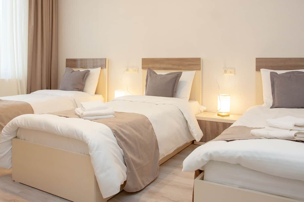 A hotel room with two beds, each with a wooden headboard, white bedding, and a bedside lamp.