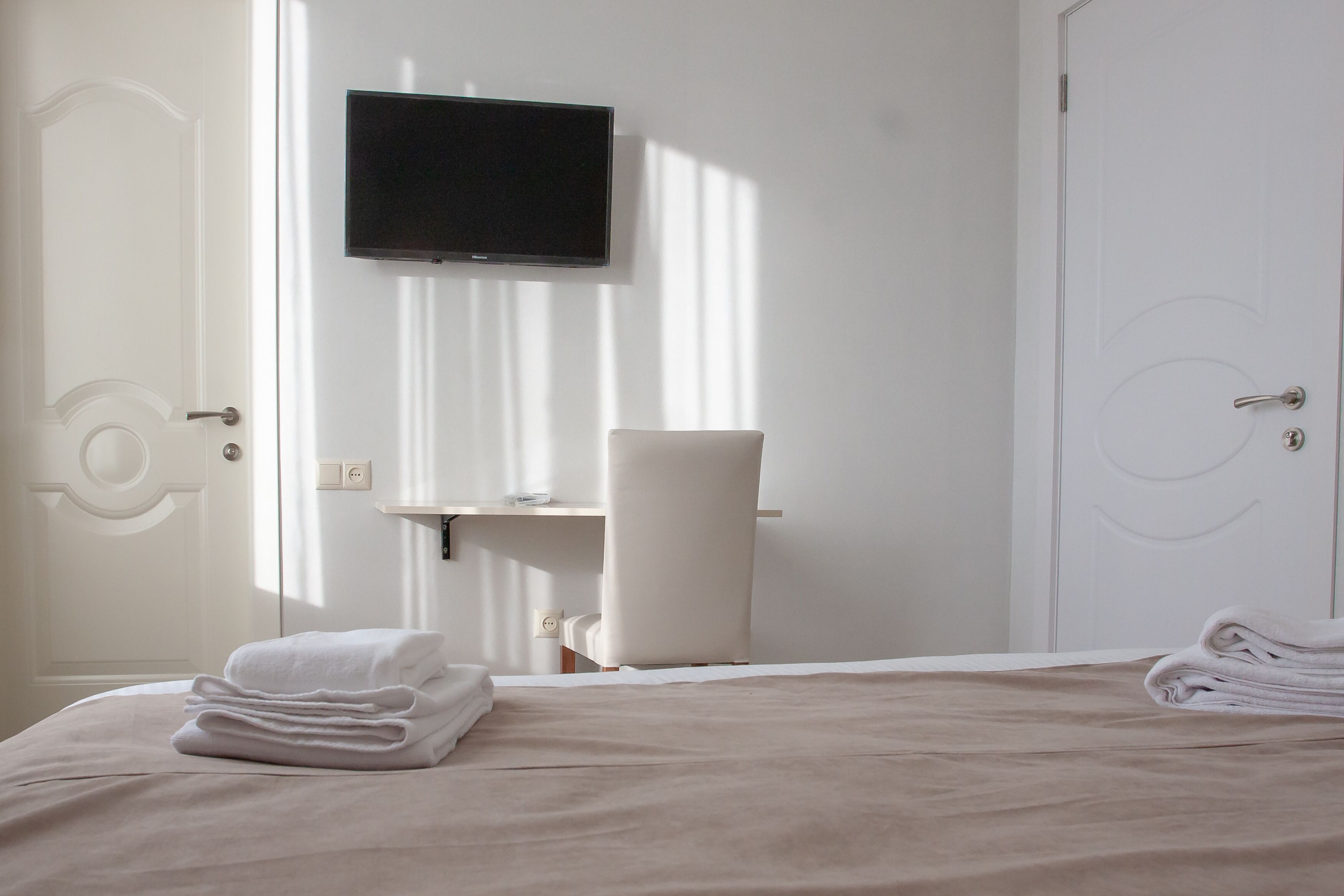 Una habitación de hotel con una cama, un televisor montado en la pared y un baño con lavabo y espejo.
