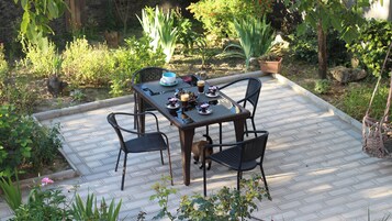 Un patio al aire libre con una mesa preparada para cuatro personas, rodeado de sillas.