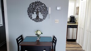 A dining area with a table, chairs, a decorative tree wall art, a vase with flowers, and a bookshelf with books. - Studio with Breathtaking Mountain View (Gatlinburg)