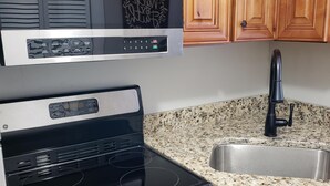 A kitchen with a stainless steel stove, a built-in oven, a granite countertop, and wooden cabinets. - Studio with Breathtaking Mountain View (Gatlinburg)