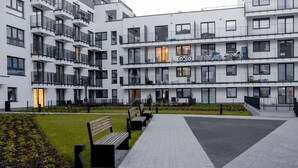 A multi-story residential building with balconies, a paved courtyard, and benches. - Crystal Apartments (Warsaw)