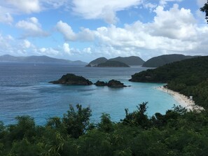 Un paisaje costero con aguas azul turquesa, afloramientos rocosos y una playa de arena.