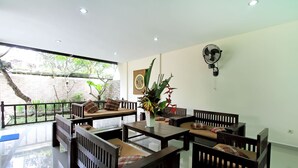 A modern interior with wooden furniture, a fan, and a view of greenery outside. - Villa 3 BR Central Seminyak mins to Beach (Seminyak)