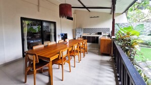 A dining area with a wooden table and chairs, a ceiling fan, and a kitchen in the background. - Villa 3 BR Central Seminyak mins to Beach (Seminyak)