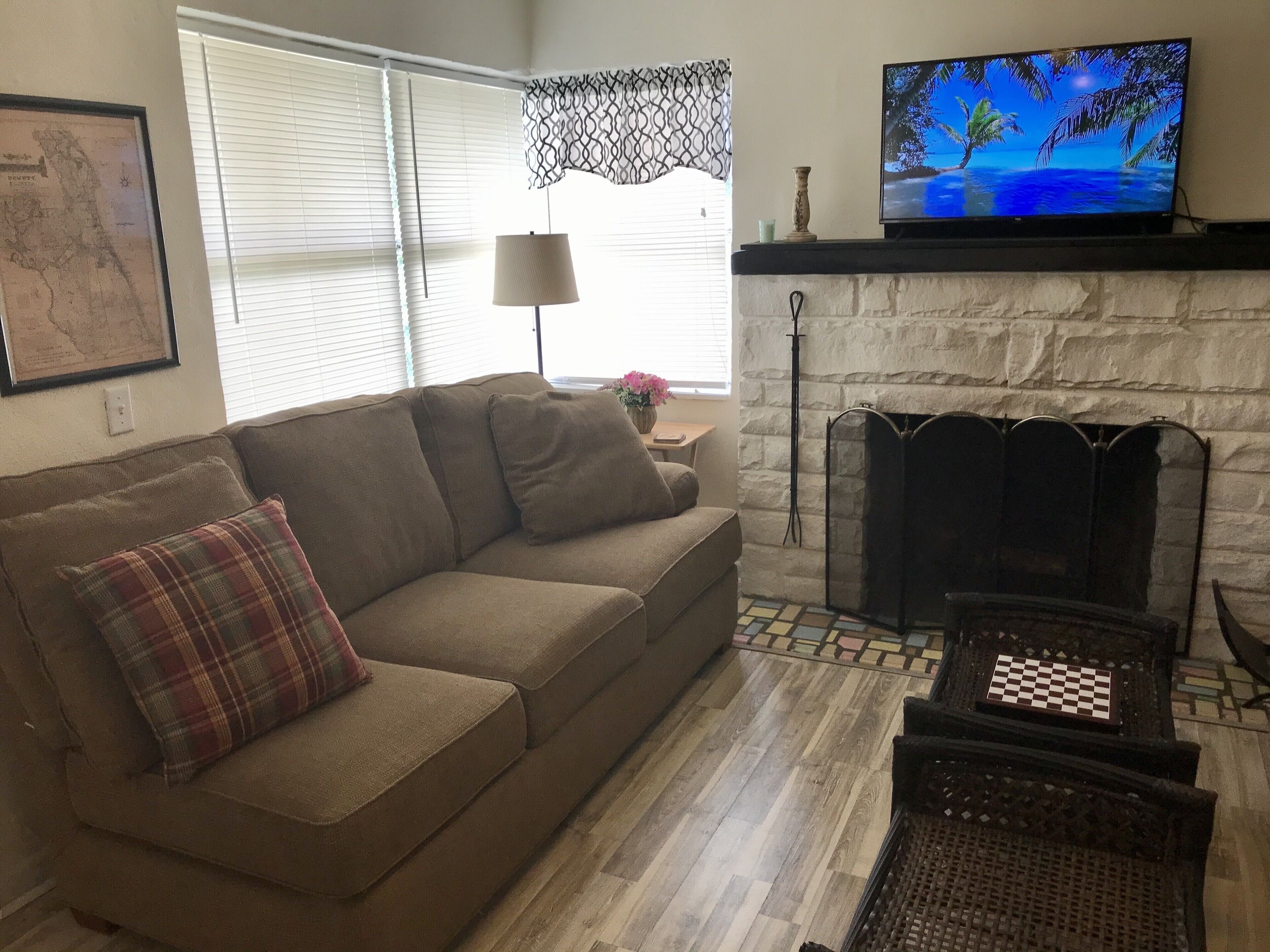 A living room with a sofa, a television, a fireplace, and a map on the wall.