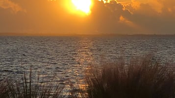Un coucher de soleil sur une étendue d’eau, avec une côte lointaine.