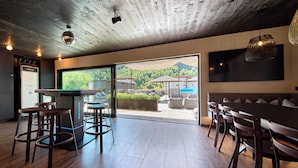 A modern kitchen with a bar area, large windows, and a view of the outdoors. - ThePoolhouse Boutique Lodge (Saalbach-Hinterglemm)