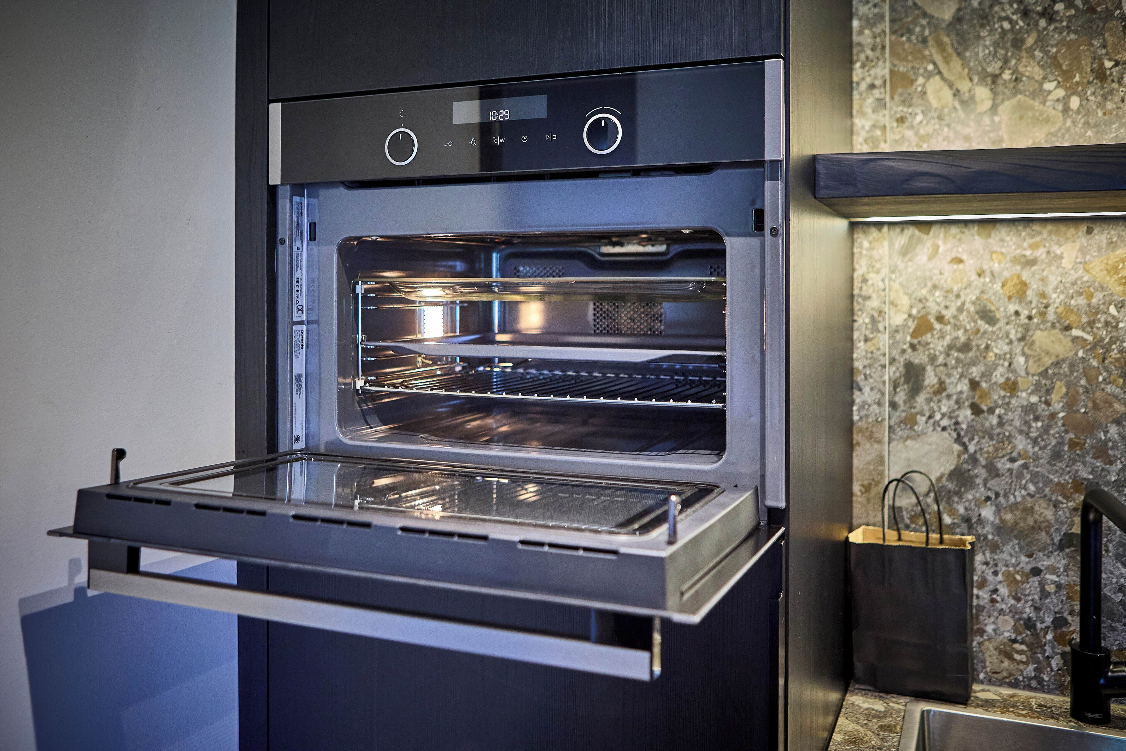 Una cocina moderna con horno empotrado, encimera y salpicadero de piedra.