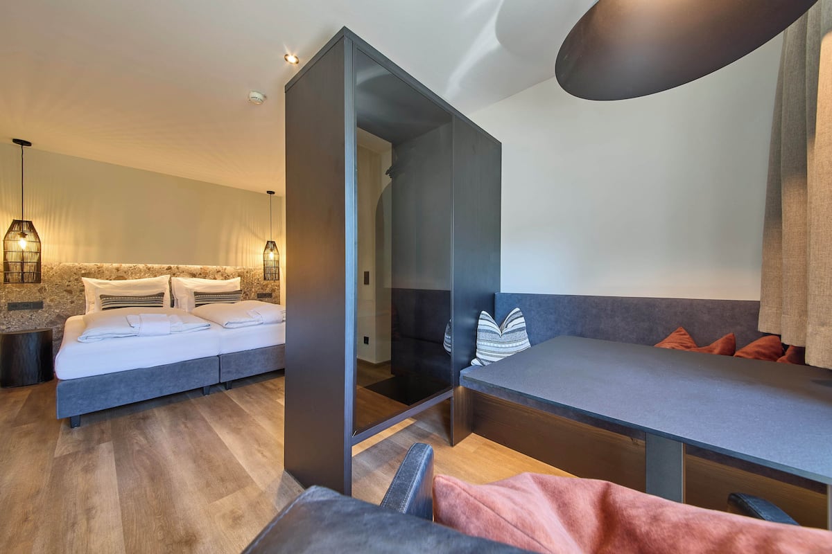 Quarto de hotel moderno com cama, escrivaninha e área de estar.