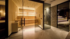 A modern interior with a wooden bench area, a glass partition, and a stone wall. - ThePoolhouse Boutique Lodge (Saalbach-Hinterglemm)