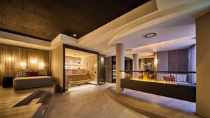 A modern hotel lobby with a seating area, a reception desk, and a staircase. - ThePoolhouse Boutique Lodge (Saalbach-Hinterglemm)