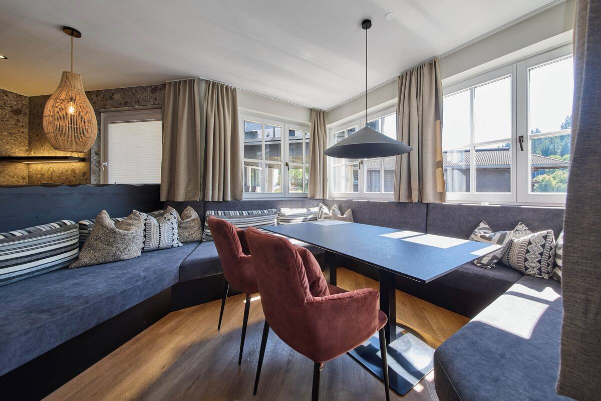 Uma sala de estar moderna com um sofá grande, uma mesa de jantar e um lustre.