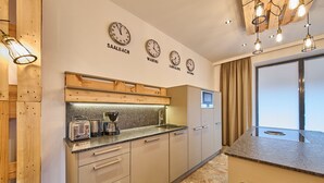 A modern kitchen with wooden cabinetry, a built-in oven, and a coffee maker.