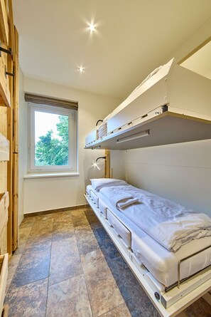 A bunk bed room with a window, wooden beams, and a tiled floor. - Appartement Bretterbude (Saalbach-Hinterglemm)