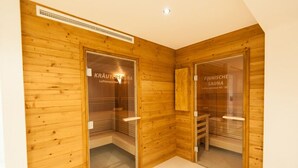 Two sauna rooms with wooden walls and glass doors, each labeled with "Kräutersauna" and "Einfache Sauna" indicating different types of saunas.