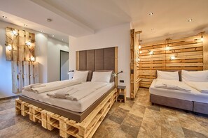 A modern bedroom with a wooden headboard, a bed with neatly folded white linens, and a small bedside table. - Appartement Bretterbude (Saalbach-Hinterglemm)