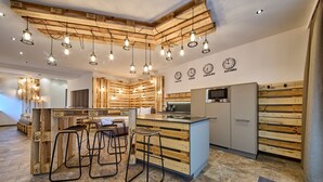 A modern kitchen with wooden accents, a central island with bar stools, and a dining area with a sofa and table.