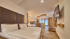 A modern hotel room with two beds, a TV, and a kitchenette.