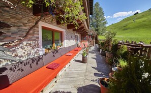 A wooden deck with a red bench, potted plants, and a stone wall.