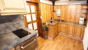A kitchen with wooden cabinets, a built-in oven, a microwave, and a coffee maker. - Chalet Appartement Alpenherz (Saalbach-Hinterglemm)