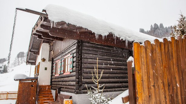A log cabin with a wooden porch and a snow-covered roof. - Chalet Appartement Alpenherz (Saalbach-Hinterglemm)