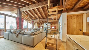 A spacious living area with a wooden ceiling, a sofa with cushions, a ladder, and a wooden cabinet. - Chalet Guter Hirte (Saalbach-Hinterglemm)
