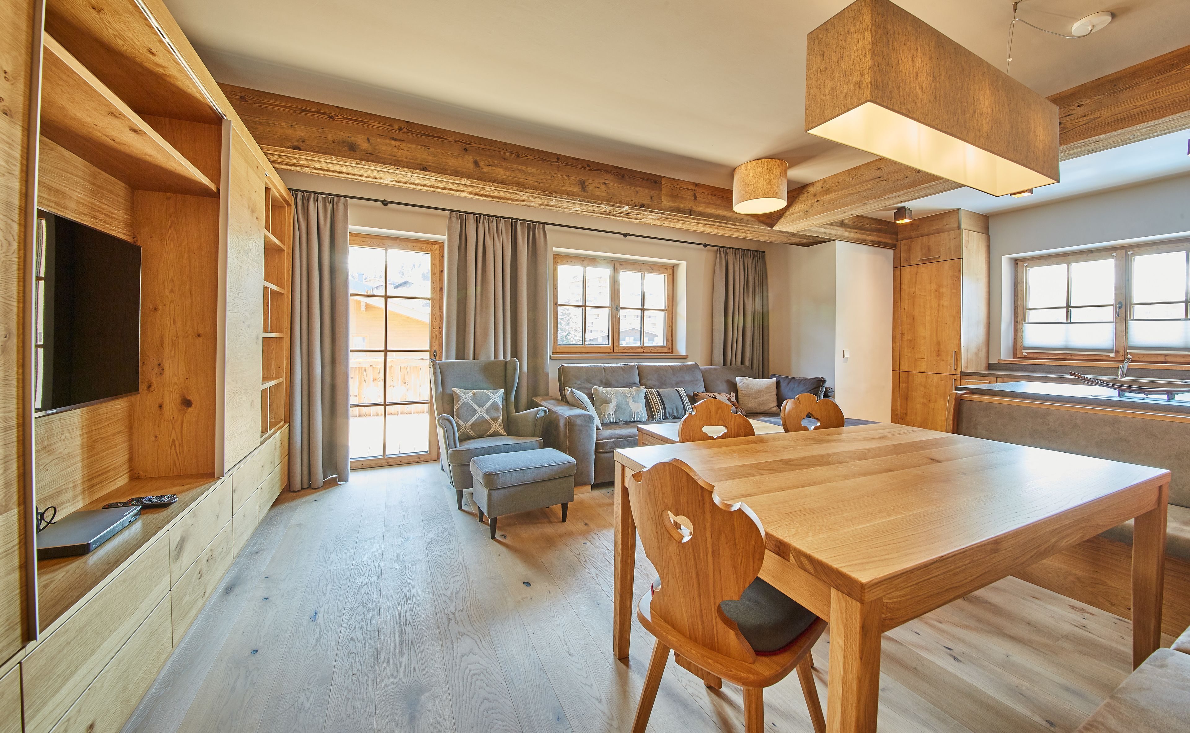 A spacious living area with a wooden dining table, sofas, and a television.