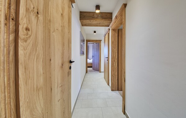 A narrow hallway with wooden doors and a tiled floor.