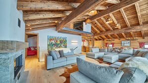A spacious living area with a high wooden ceiling, a fireplace, and a large sofa set. - Chalet Guter Hirte (Saalbach-Hinterglemm)
